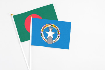 Northern Mariana Islands and Bangladesh stick flags on white background. High quality fabric, miniature national flag. Peaceful global concept.White floor for copy space.