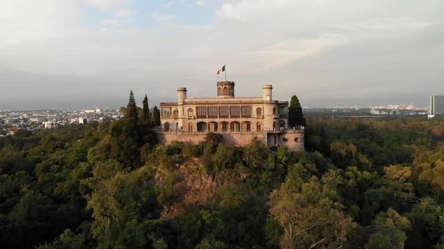 Drone slowly ascending in front of Chapultepec Castle to reveal Mexico City skyline at sunrise