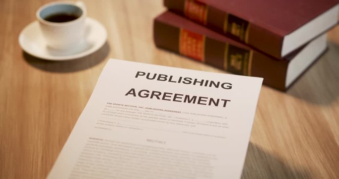 A paper showing a publishing contract or agreement on a table. The video pans across the agreement.
