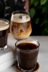 Filter coffee and iced latte in glasses served on a white table