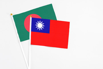 Obraz premium Taiwan and Bangladesh stick flags on white background. High quality fabric, miniature national flag. Peaceful global concept.White floor for copy space.