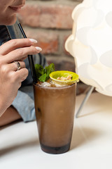 Woman drinking tropical party cocktail from a highball glass in a restaurant