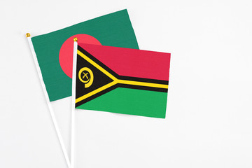 Vanuatu and Bangladesh stick flags on white background. High quality fabric, miniature national flag. Peaceful global concept.White floor for copy space.