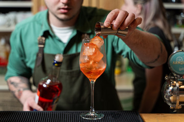 Bartender is making aperol spritz on a bar counter in a restaurant