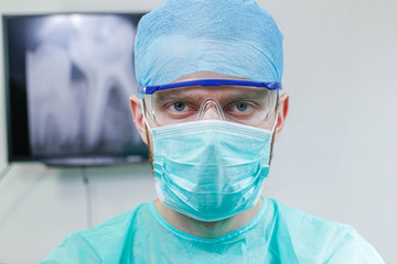 Young male dentist doctor in uniform and goggles in the office.