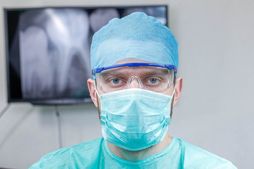 Young male dentist doctor in uniform and goggles in the office.