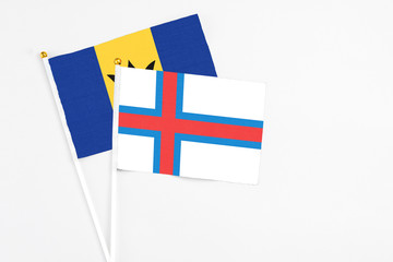 Faroe Islands and Barbados stick flags on white background. High quality fabric, miniature national flag. Peaceful global concept.White floor for copy space.