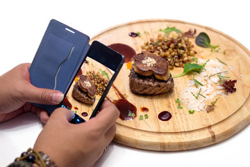 mobile phone taking a picture of Grilled Fillet of Veal topped with Foie Gras. © lmanju