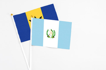 Guatemala and Barbados stick flags on white background. High quality fabric, miniature national flag. Peaceful global concept.White floor for copy space.