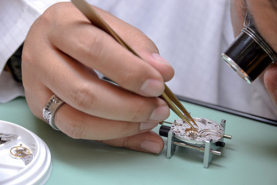 Watchmaker picked up the tiny escape wheel part very carefully to mainplate