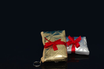 Small women bag to carry everyday personal items tied with a red bow, make up bag with cosmetics, gift, isolated on black background.