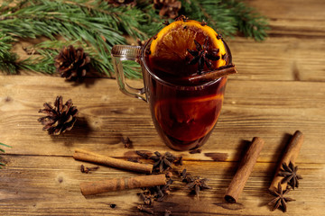 Christmas mulled wine with spices and fir tree branches and cones on wooden table
