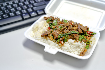 Packed lunch fried basil leaf with beef eat with rice on table work