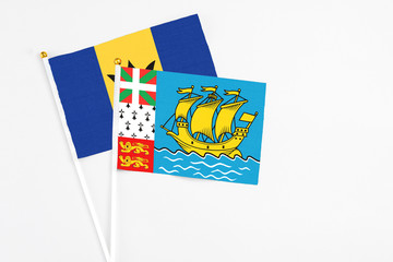 Saint Pierre And Miquelon and Barbados stick flags on white background. High quality fabric, miniature national flag. Peaceful global concept.White floor for copy space.