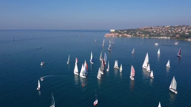 Left side moving drone aerial view of Barcolana sailing boat race regatta event in Trieste, Italy sunny day