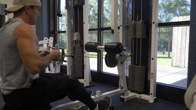 Man exercising, doing a cable row on a machine in the gym, training, working out.