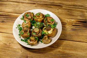 Baked mushrooms in plate on wooden table