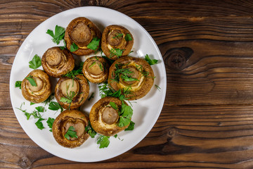 Baked mushrooms in plate on wooden table. Top view