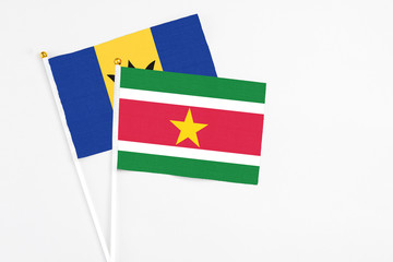 Suriname and Barbados stick flags on white background. High quality fabric, miniature national flag. Peaceful global concept.White floor for copy space.
