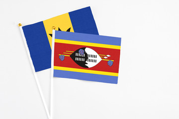 Swaziland and Barbados stick flags on white background. High quality fabric, miniature national flag. Peaceful global concept.White floor for copy space.