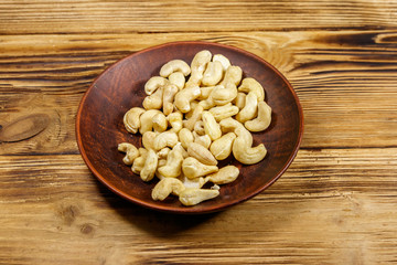 Ceramic plate with raw cashew nuts on a wooden table