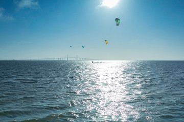 Kite surfing in the sea with the bridge over sea in background.