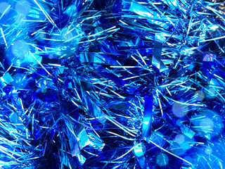 Christmas background, blue texture with abstract christmas decorations. Concept background for New Year and Christmas holidays 2020 with sparkles, needles and tinsel. Bright luminous pattern copyspace