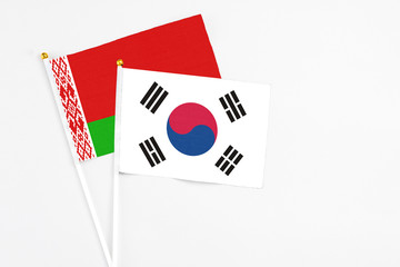 South Korea and Belarus stick flags on white background. High quality fabric, miniature national flag. Peaceful global concept.White floor for copy space.