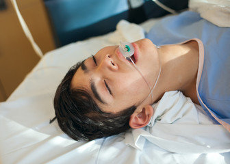 Obraz na płótnie Canvas Young teen boy unconscious in hospital recovery room on gurney