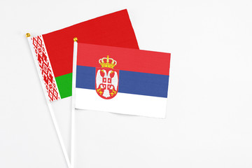 Serbia and Belarus stick flags on white background. High quality fabric, miniature national flag. Peaceful global concept.White floor for copy space.