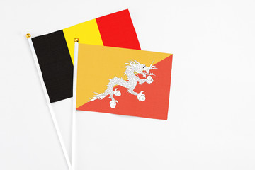Bhutan and Belgium stick flags on white background. High quality fabric, miniature national flag. Peaceful global concept.White floor for copy space.