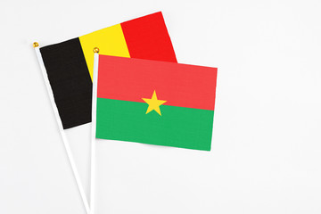 Burkina Faso and Belgium stick flags on white background. High quality fabric, miniature national flag. Peaceful global concept.White floor for copy space.