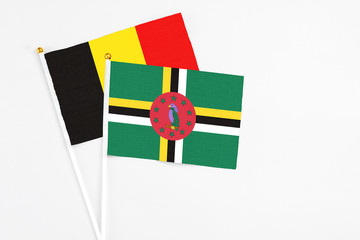 Fototapeta premium Dominica and Belgium stick flags on white background. High quality fabric, miniature national flag. Peaceful global concept.White floor for copy space.