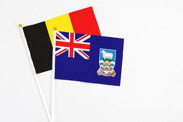 Fototapeta premium Falkland Islands and Belgium stick flags on white background. High quality fabric, miniature national flag. Peaceful global concept.White floor for copy space.