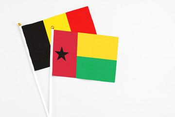 Guinea Bissau and Belgium stick flags on white background. High quality fabric, miniature national flag. Peaceful global concept.White floor for copy space.