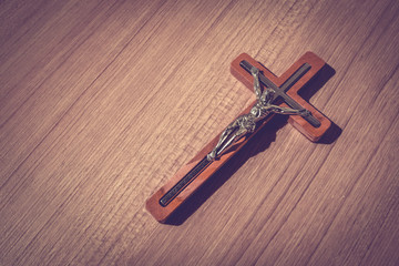 Scene of the wooden cross with metal Jesus Christ with light and shadow and bible on wooden floor, good friday, easter, with blank copy space