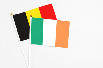 Ireland and Belgium stick flags on white background. High quality fabric, miniature national flag. Peaceful global concept.White floor for copy space.