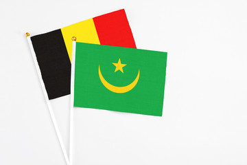 Mauritania and Belgium stick flags on white background. High quality fabric, miniature national flag. Peaceful global concept.White floor for copy space.