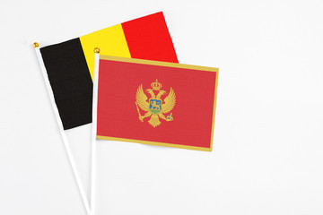 Montenegro and Belgium stick flags on white background. High quality fabric, miniature national flag. Peaceful global concept.White floor for copy space.