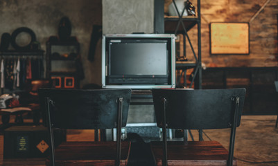 Blank space of monitor screen on vintage cafe background and retro black metal chair, use to put...