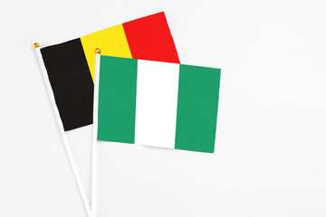 Fototapeta premium Nigeria and Belgium stick flags on white background. High quality fabric, miniature national flag. Peaceful global concept.White floor for copy space.