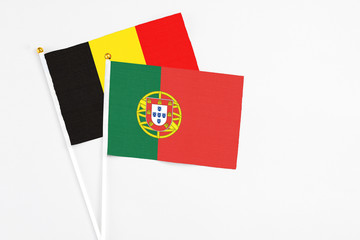 Portugal and Belgium stick flags on white background. High quality fabric, miniature national flag. Peaceful global concept.White floor for copy space.