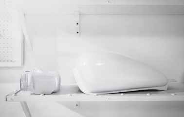 White metal motorcycle tank in custom workshop with tools equipment environment, white space and blank copy space