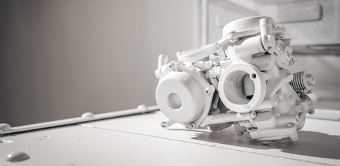 White carburetor engine of motorcycle on metal table in all white garage, with blank copy space, motorcycle fragment