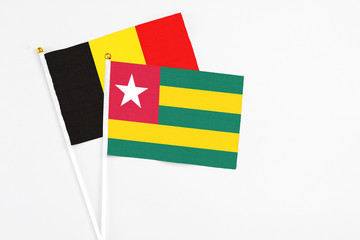 Togo and Belgium stick flags on white background. High quality fabric, miniature national flag. Peaceful global concept.White floor for copy space.