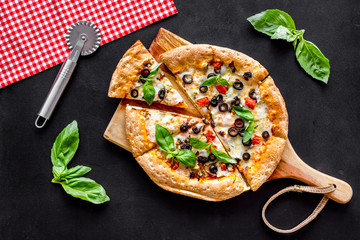Pizza with tomato, basil, olives, cheese on black background top view