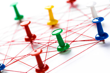 Network with colorful pins and string,  linked together with string on a white background...