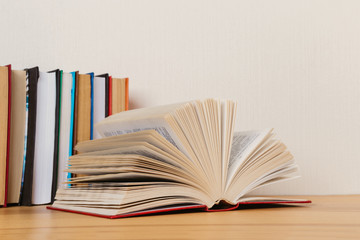 Simple composition of many hardback books, raw of books on wooden table and light  background