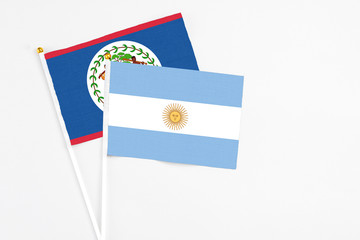 Argentina and Belize stick flags on white background. High quality fabric, miniature national flag. Peaceful global concept.White floor for copy space.