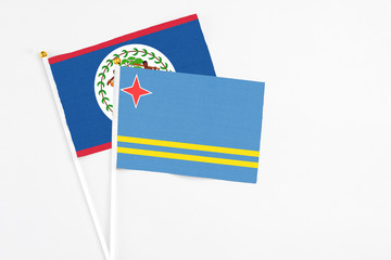 Aruba and Belize stick flags on white background. High quality fabric, miniature national flag. Peaceful global concept.White floor for copy space.